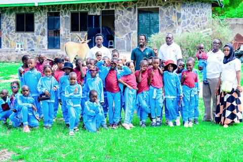 Pupils and staff standing while an eland grazes nearby