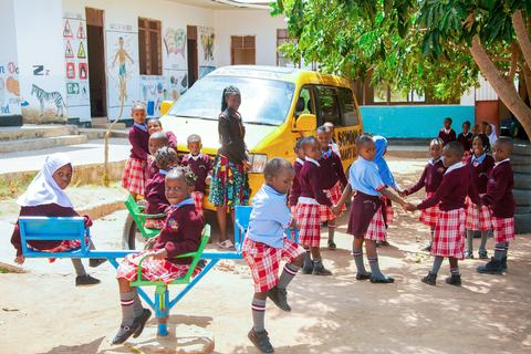 Pupils playing on the playground roundabout near the school van
